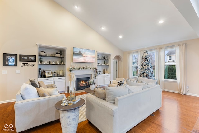 living room with hardwood / wood-style flooring, high vaulted ceiling, and a tile fireplace