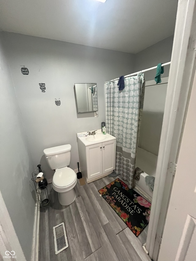 full bathroom with hardwood / wood-style floors, vanity, toilet, and shower / tub combo