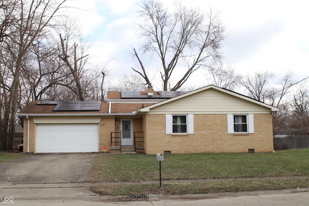 ranch-style house featuring solar panels, a garage, and a front yard