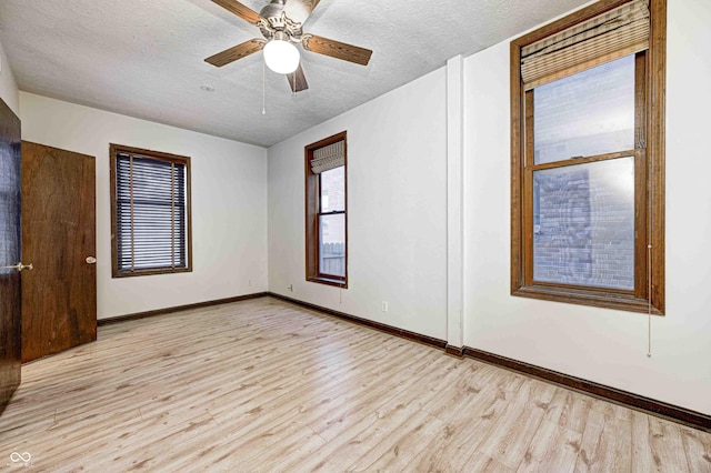 empty room with ceiling fan, light wood-type flooring, and a textured ceiling