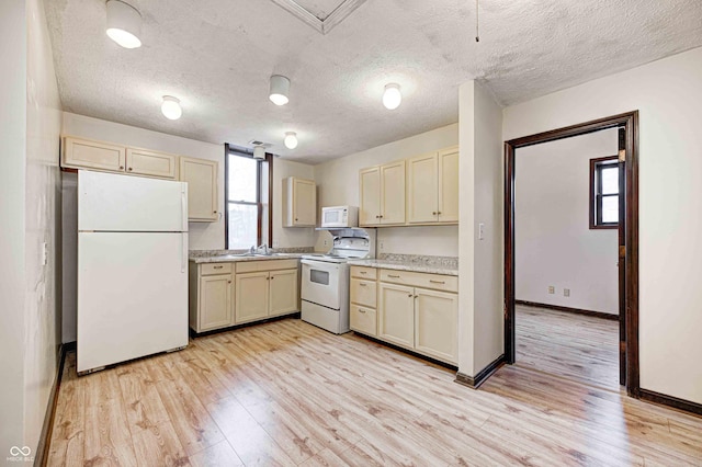 kitchen featuring cream cabinetry, light hardwood / wood-style floors, white appliances, and a textured ceiling