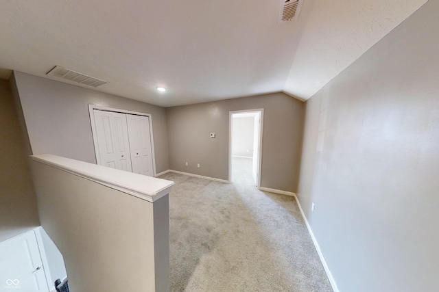 hallway featuring an upstairs landing, baseboards, visible vents, and light colored carpet