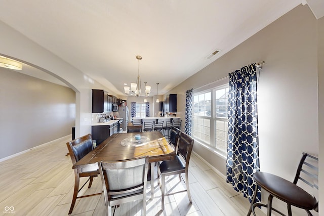 dining area featuring arched walkways, baseboards, visible vents, and a notable chandelier