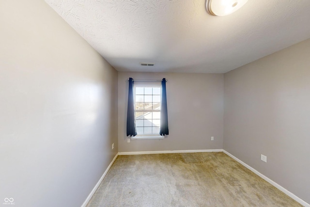 empty room featuring a textured ceiling, carpet flooring, visible vents, and baseboards