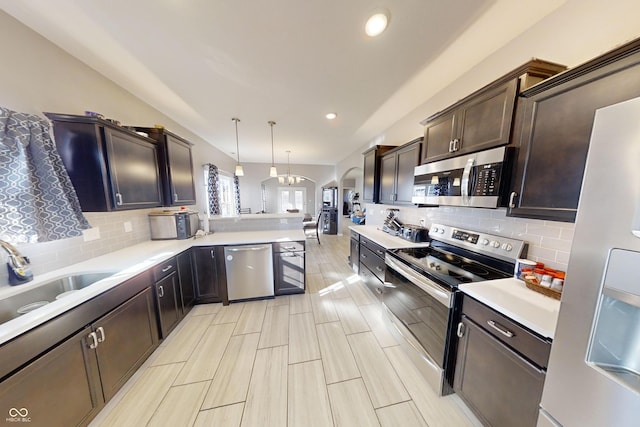 kitchen with stainless steel appliances, light countertops, a sink, dark brown cabinetry, and a peninsula