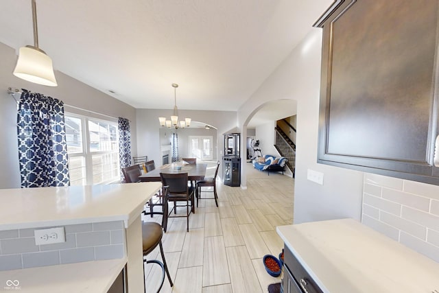 dining room with arched walkways, stairway, wood tiled floor, and a notable chandelier