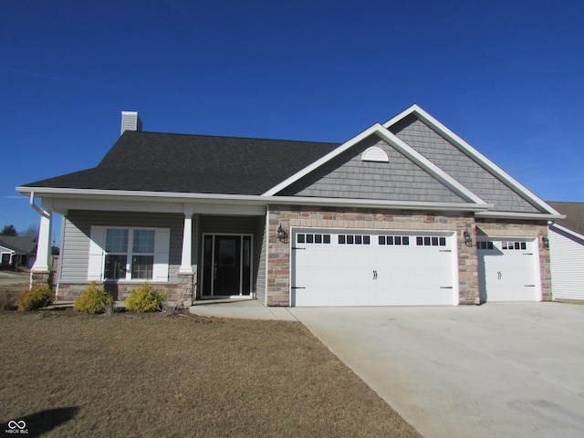 craftsman-style home with an attached garage, covered porch, stone siding, driveway, and a chimney