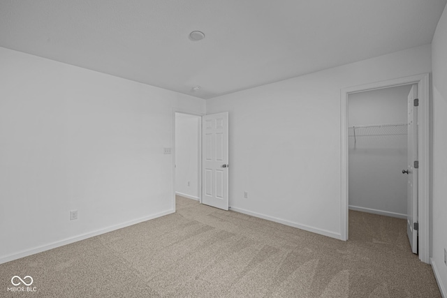 unfurnished bedroom featuring a spacious closet, light colored carpet, and a closet