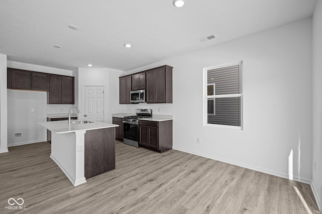 kitchen featuring sink, light hardwood / wood-style flooring, stainless steel appliances, and a center island with sink