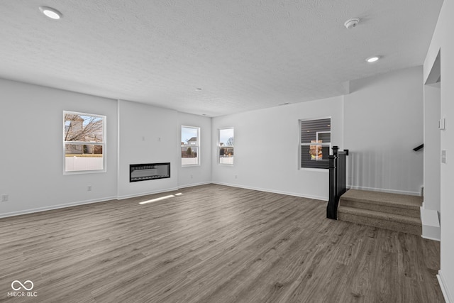 unfurnished living room with hardwood / wood-style flooring and a textured ceiling