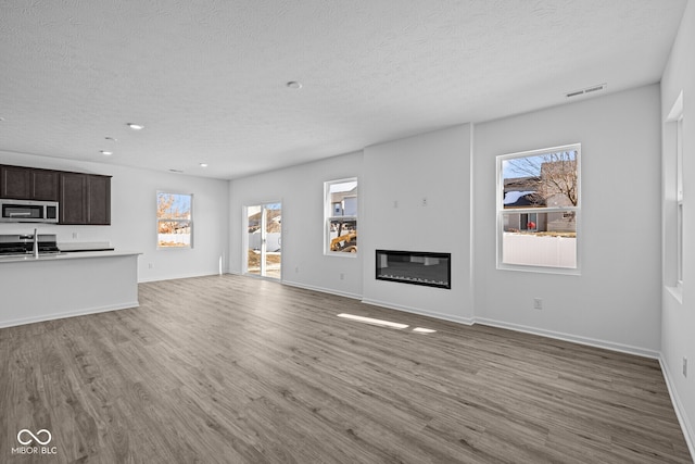 unfurnished living room with hardwood / wood-style flooring, plenty of natural light, and a textured ceiling