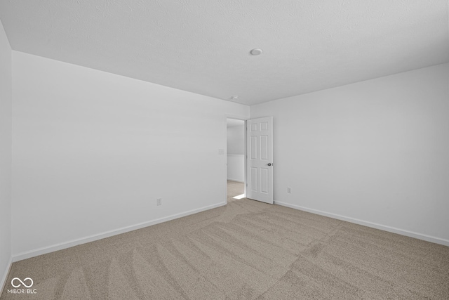 unfurnished room with light colored carpet and a textured ceiling