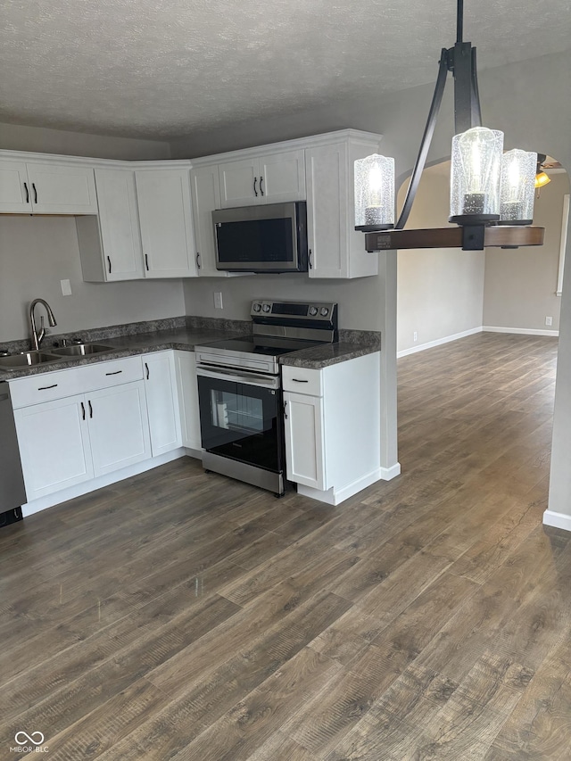 kitchen featuring white cabinetry, sink, hanging light fixtures, stainless steel appliances, and dark hardwood / wood-style floors