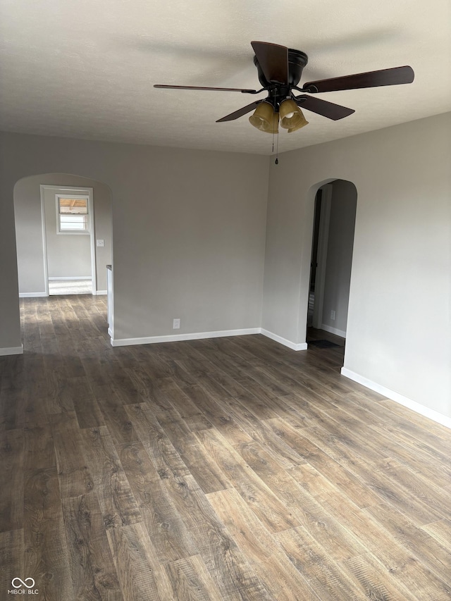 empty room with ceiling fan, dark hardwood / wood-style flooring, and a textured ceiling