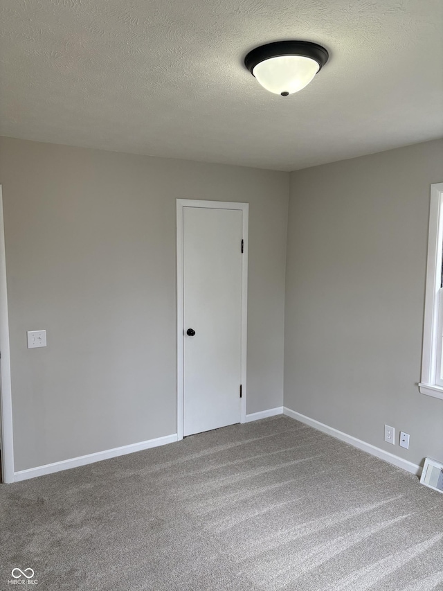 spare room featuring carpet floors and a textured ceiling