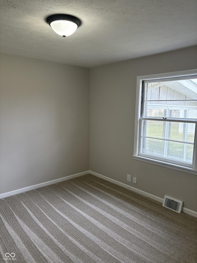 carpeted empty room with a textured ceiling