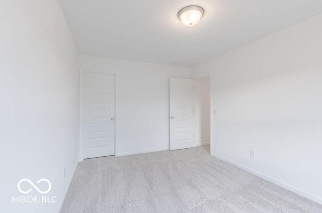 unfurnished bedroom with light colored carpet and a closet