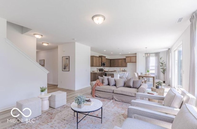 living room with light hardwood / wood-style floors and an inviting chandelier