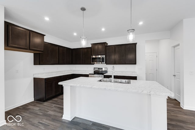 kitchen featuring a center island with sink, dark wood-style floors, decorative light fixtures, stainless steel appliances, and a sink