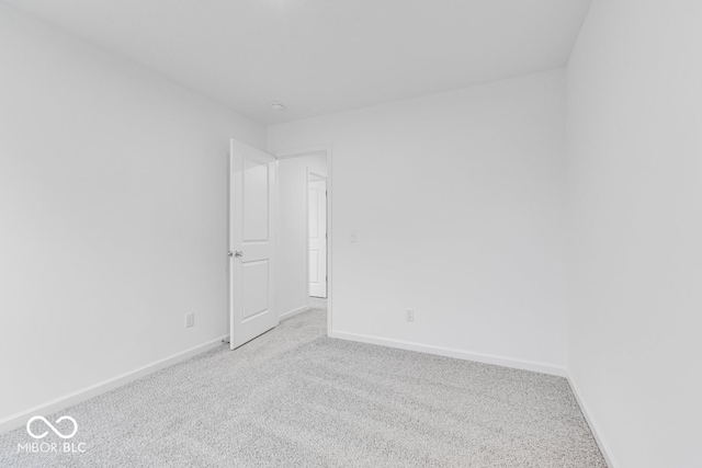 spare room featuring baseboards and light colored carpet