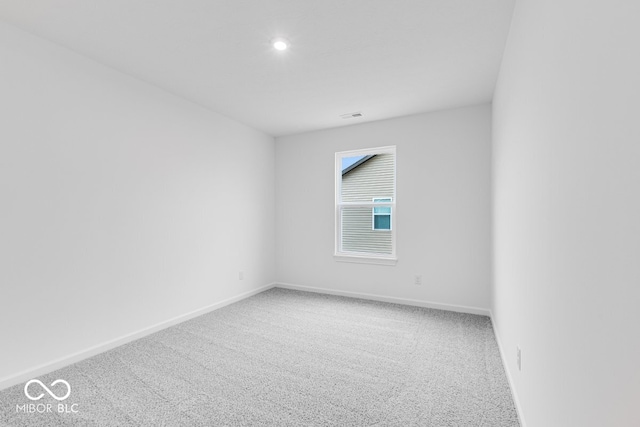 spare room with carpet flooring, visible vents, and baseboards