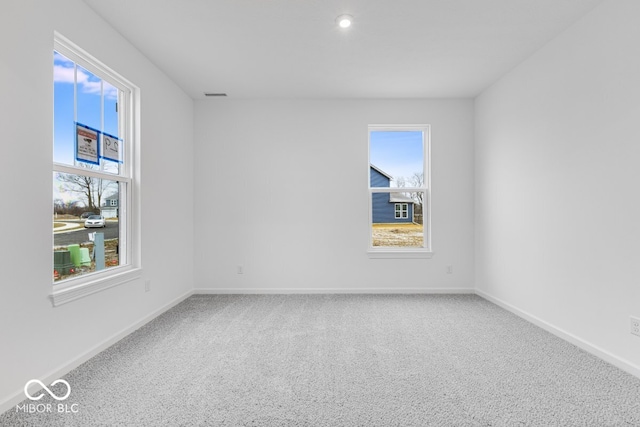 carpeted spare room with visible vents and baseboards