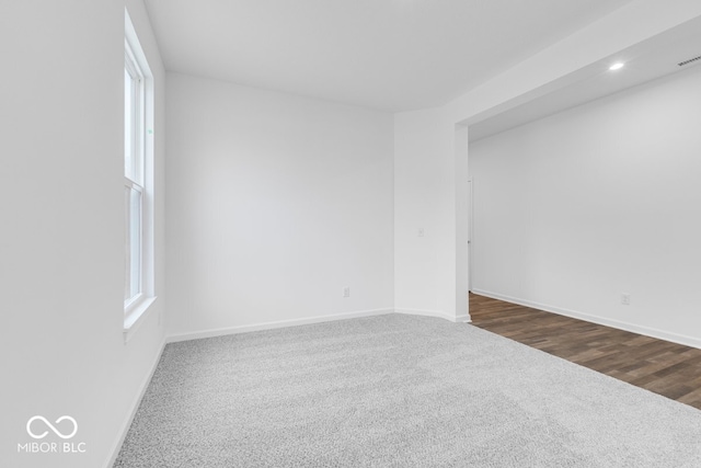 unfurnished room featuring dark colored carpet, a healthy amount of sunlight, and baseboards