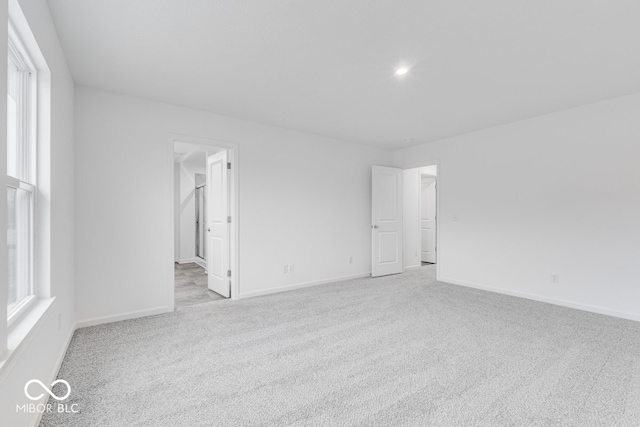 spare room with baseboards and light colored carpet