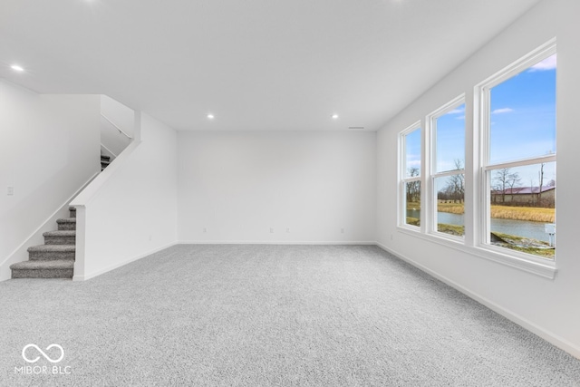 interior space with carpet, a water view, baseboards, and stairs