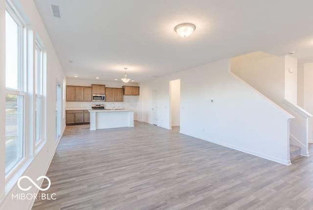 unfurnished living room featuring visible vents, baseboards, stairway, light wood-type flooring, and recessed lighting