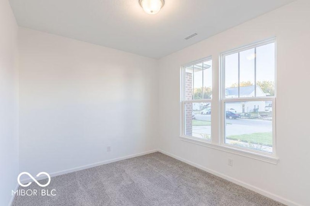 carpeted spare room with visible vents and baseboards