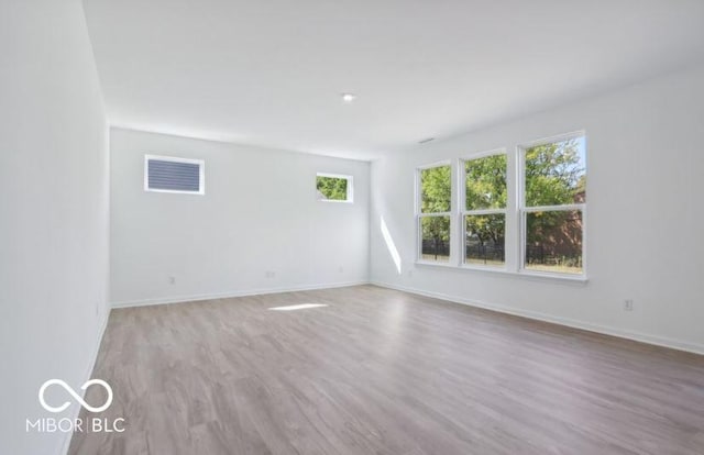 empty room featuring light wood-style floors, visible vents, and baseboards