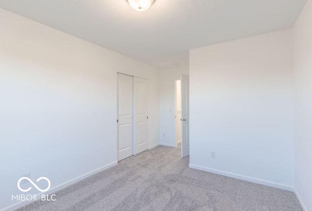 unfurnished bedroom featuring baseboards, a closet, and light colored carpet