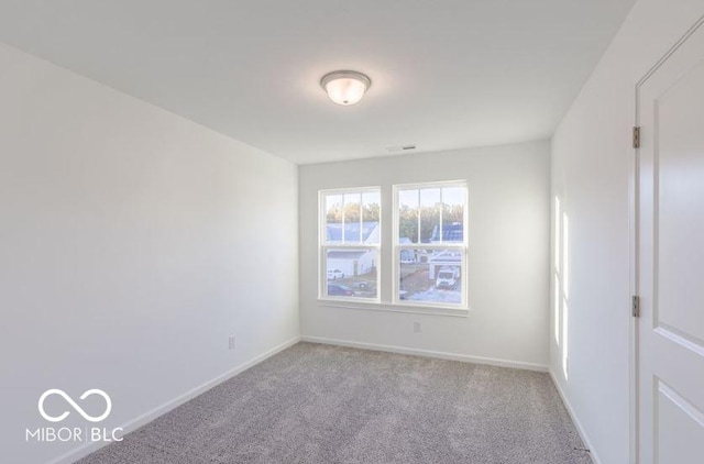 spare room featuring light carpet, visible vents, and baseboards