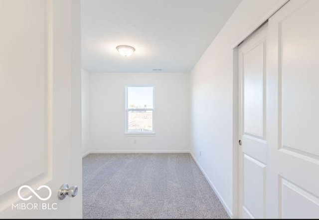 unfurnished room featuring light colored carpet and baseboards