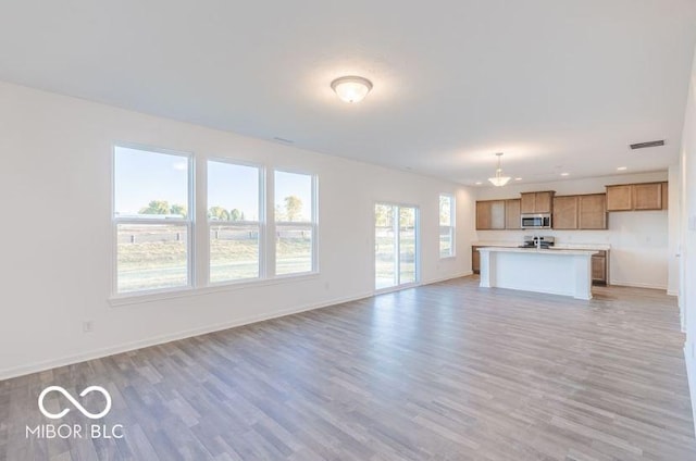 unfurnished living room featuring light wood finished floors, recessed lighting, visible vents, and baseboards