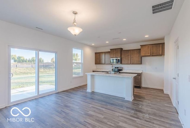 kitchen with visible vents, light countertops, appliances with stainless steel finishes, hanging light fixtures, and brown cabinets