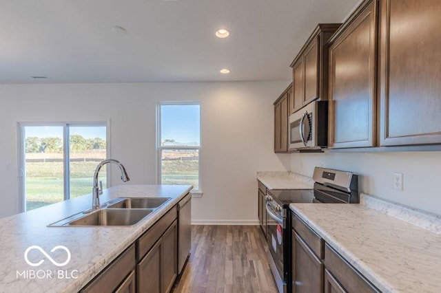 kitchen with baseboards, appliances with stainless steel finishes, wood finished floors, a sink, and recessed lighting