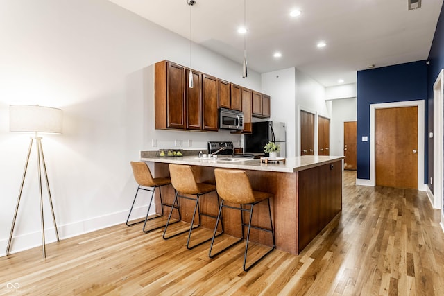 kitchen featuring appliances with stainless steel finishes, sink, a breakfast bar area, light hardwood / wood-style floors, and kitchen peninsula