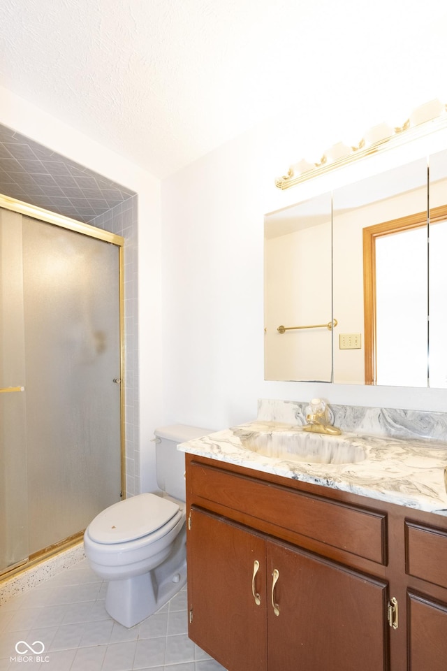 bathroom featuring tile patterned flooring, vanity, toilet, and an enclosed shower