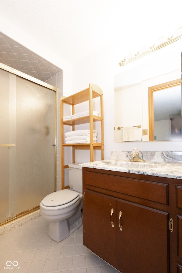 bathroom featuring tile patterned floors, vanity, toilet, and a shower with door