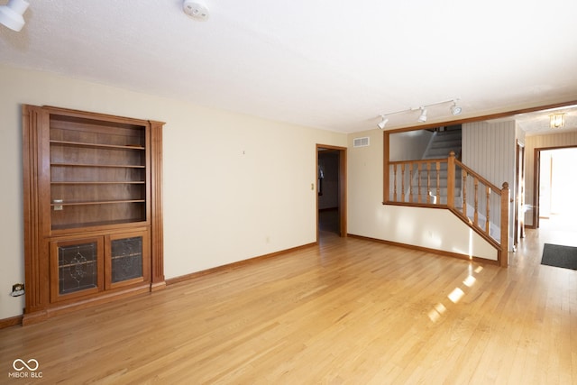 unfurnished living room featuring a textured ceiling and light hardwood / wood-style flooring