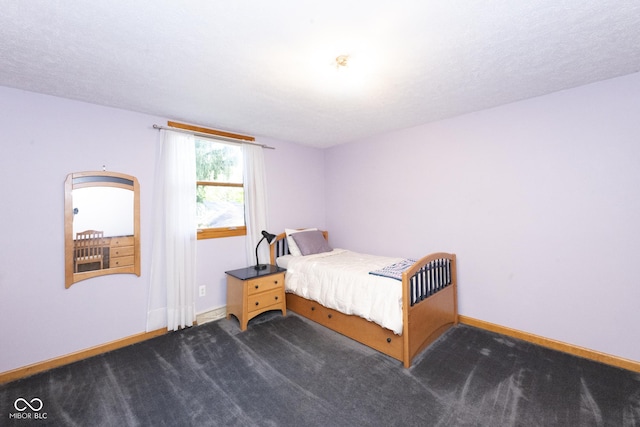 bedroom with dark carpet and a textured ceiling