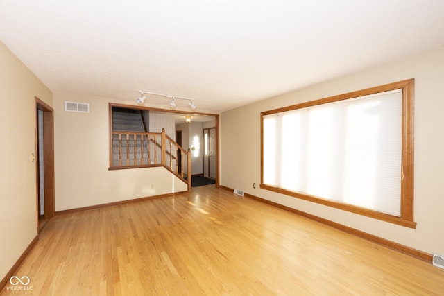 unfurnished living room with rail lighting and light hardwood / wood-style flooring