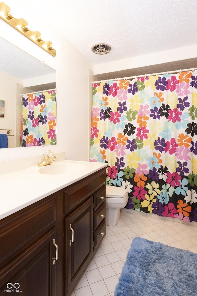 bathroom with tile patterned flooring, vanity, a textured ceiling, and toilet