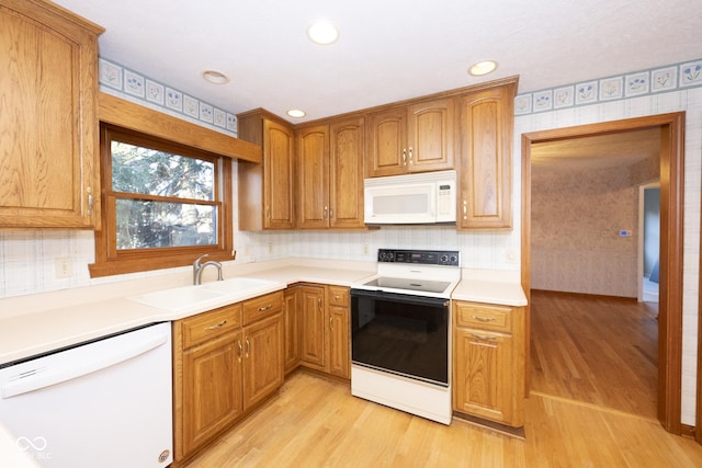 kitchen featuring light wood-type flooring, white appliances, sink, and tasteful backsplash