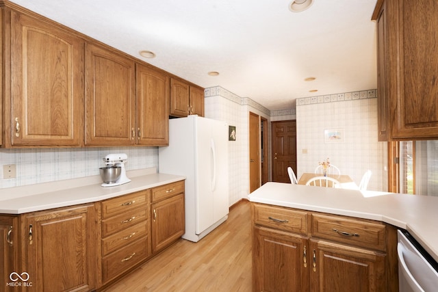 kitchen with backsplash, dishwasher, white fridge, and light hardwood / wood-style floors