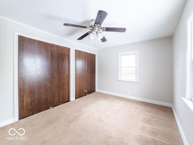 unfurnished bedroom featuring multiple closets, carpet, and ceiling fan