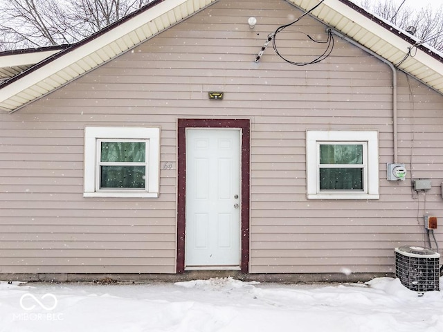 snow covered property entrance featuring cooling unit