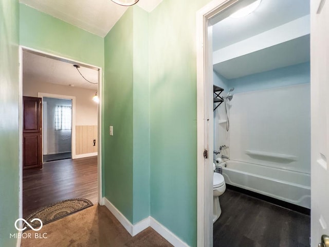 bathroom featuring hardwood / wood-style flooring, washtub / shower combination, and toilet